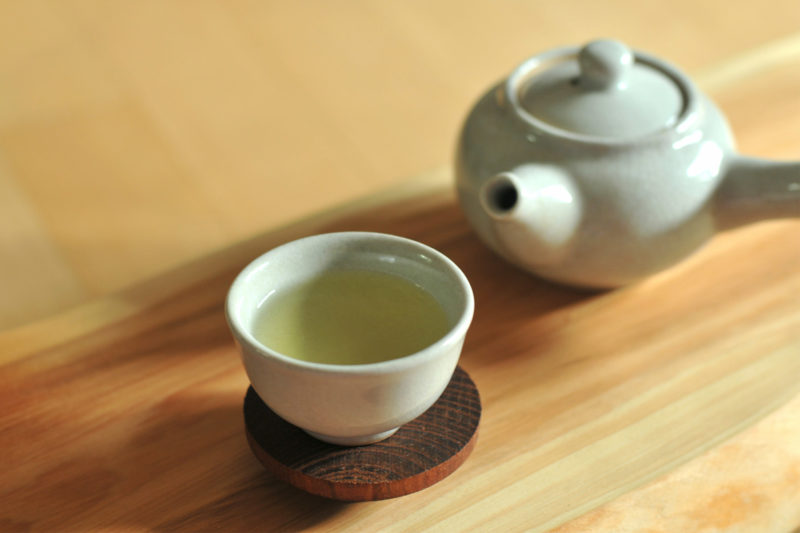 Green Tea pot and cup of tea resting on a table