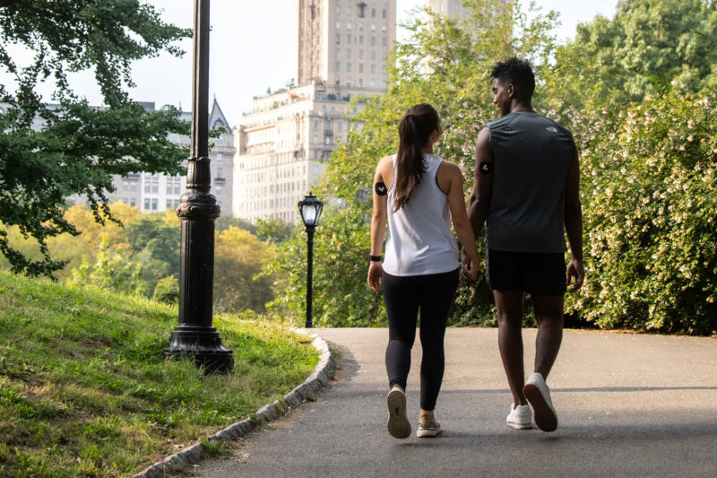 man and woman walking through central park wearing the Levels CGM