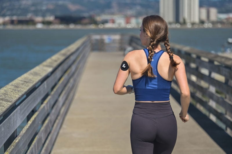 Woman jogging wearing a continuous glucose monitor