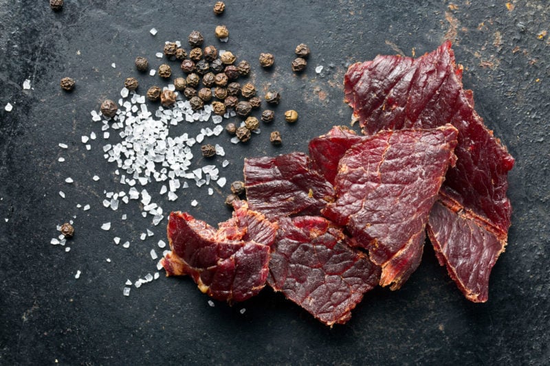 pieces of beef jerky on cutting board with spices